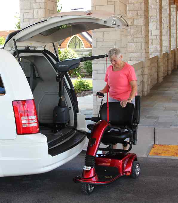 lady operating the Bruno Curb-sider mobility scooter lift that is installed inside her white minivan