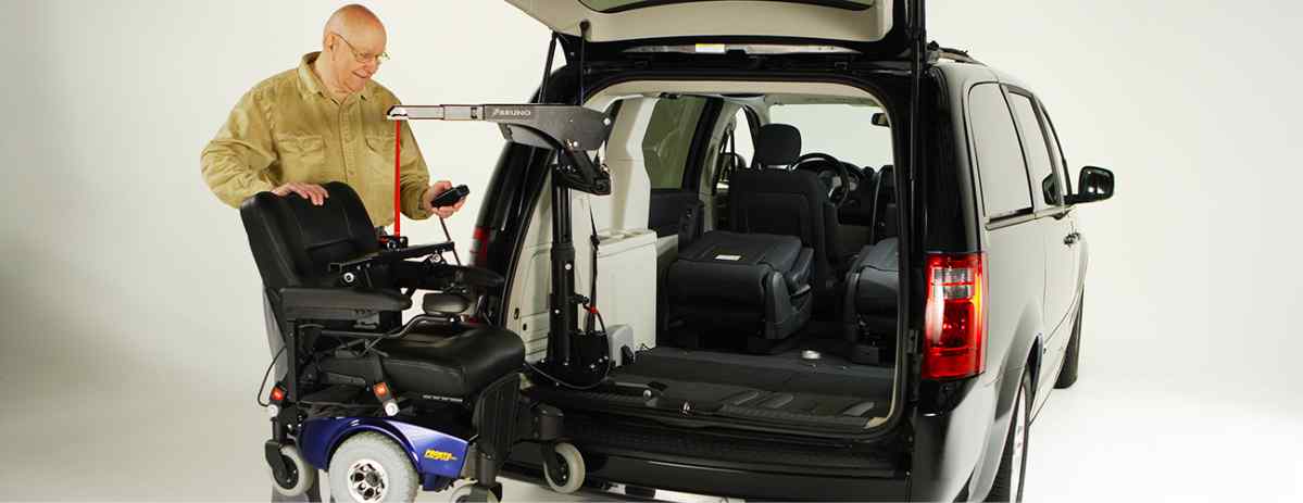 Man operating the Bruno Big-Lifter installed inside rear hatch of black minivan