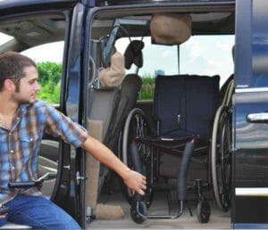 man loading his wheelchair into a black minivan using an adapt solutions Hi-lift manual wheelchair lift