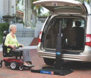 Harmar hybrid internal external mobility scooter lift in a silver minivan with a lady in a green shirt driving her mobility scooter onto the platform