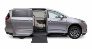 Side view of a silver, VMI Chrysler Pacifica wheelchair accessible van with ramp out