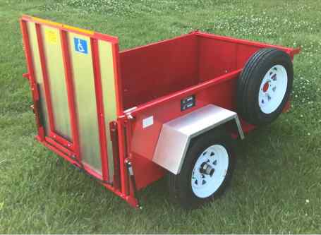 Red Scootatrailer wheelchair & scooter carrier trailer sitting in a grassy field