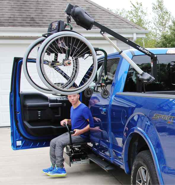 Man sitting in his truck in his driveway unloading his manual wheelchair using a Bruno Out-Rider wheelchair lift