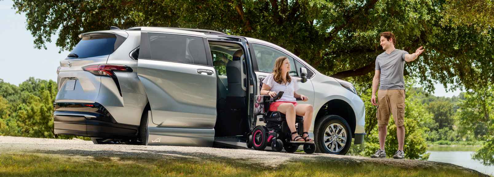 Lady in wheelchair coming out of a Silver VMI 2021 Toyota hybrid wheelchair van near a lake