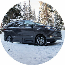 Image in a circle of a VMI Toyota Sienna Hybrid AWD Wheelchair van sitting in the snow in a forest