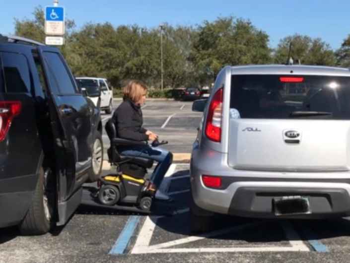 lady coming down wheelchair ram with a car blocking her exit