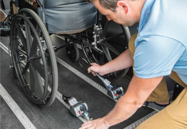 Man installing wheelchair restraints in VMI Promaster ADA Wheelchair Van