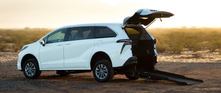 White Toyota Sienna Hybrid Rear-Entry Wheelchair Van parked in a desert scene with ramp out.